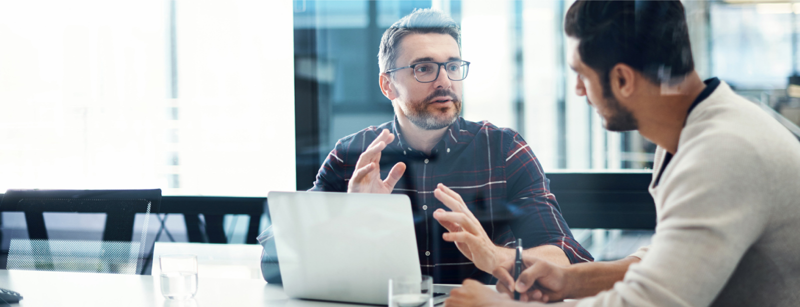 Two men having a discussion in front of a computer.