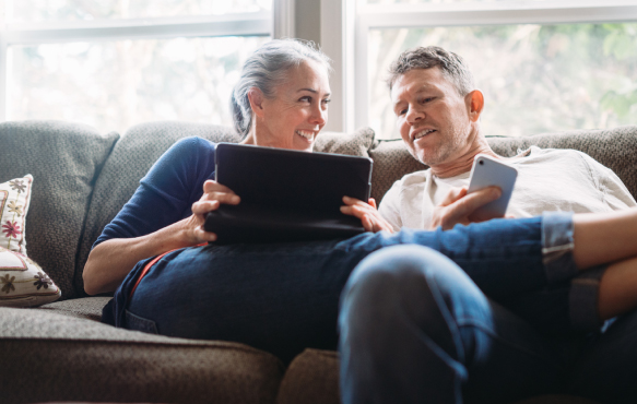 PIcture of man and woman sitting on couch with laptop.